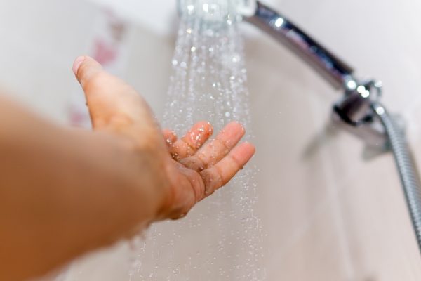 Hand voelt temperatuur van water in de douche