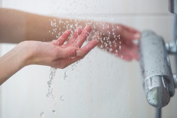 Hand voelt aan temperatuur van water in de douche